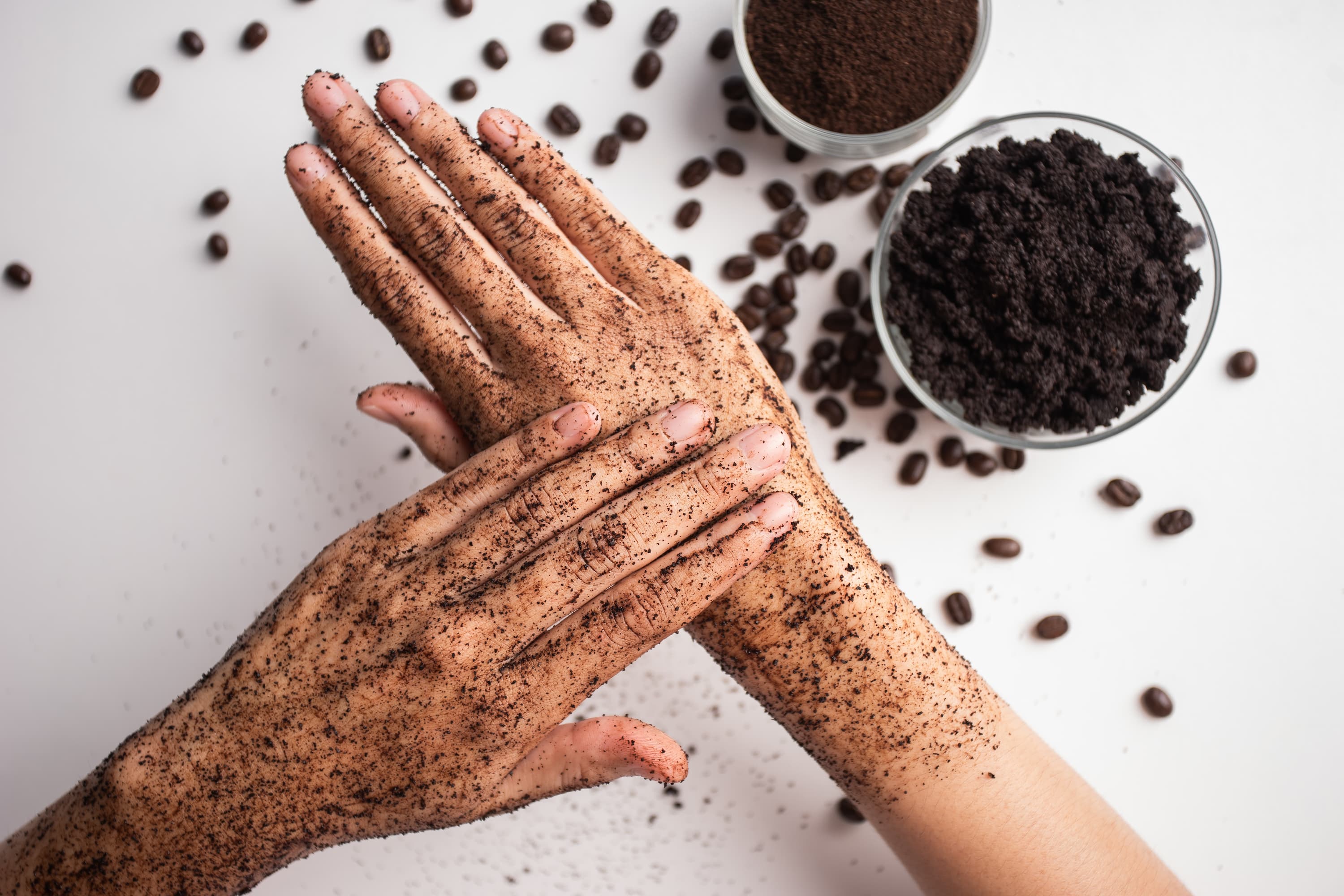 Hände mit aufgetragenem Kaffeepeeling, natürliche Hautpflege mit Kaffeesatz.