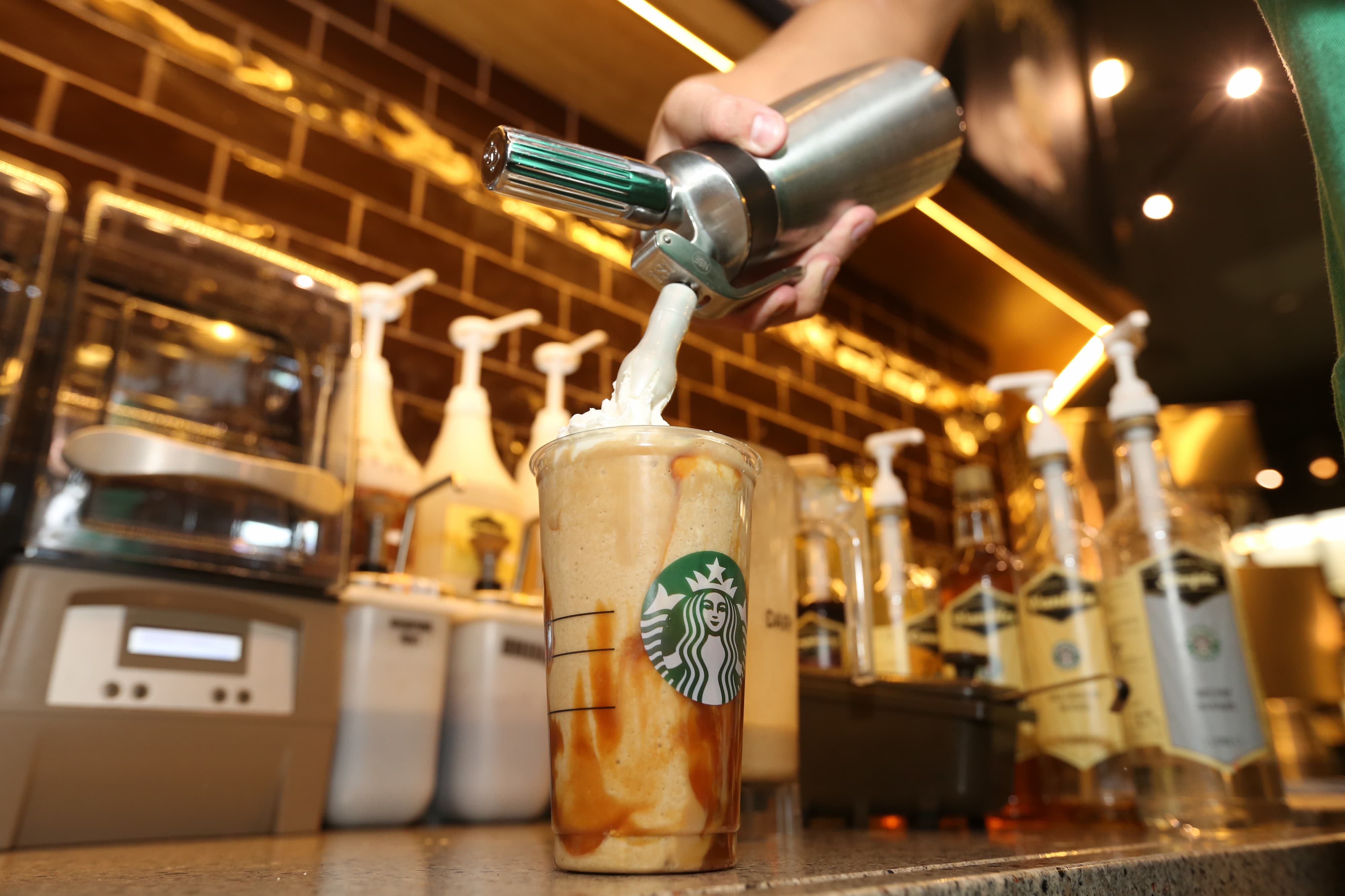 Zubereitung eines Starbucks Frappuccinos mit Karamell und Sahne.
