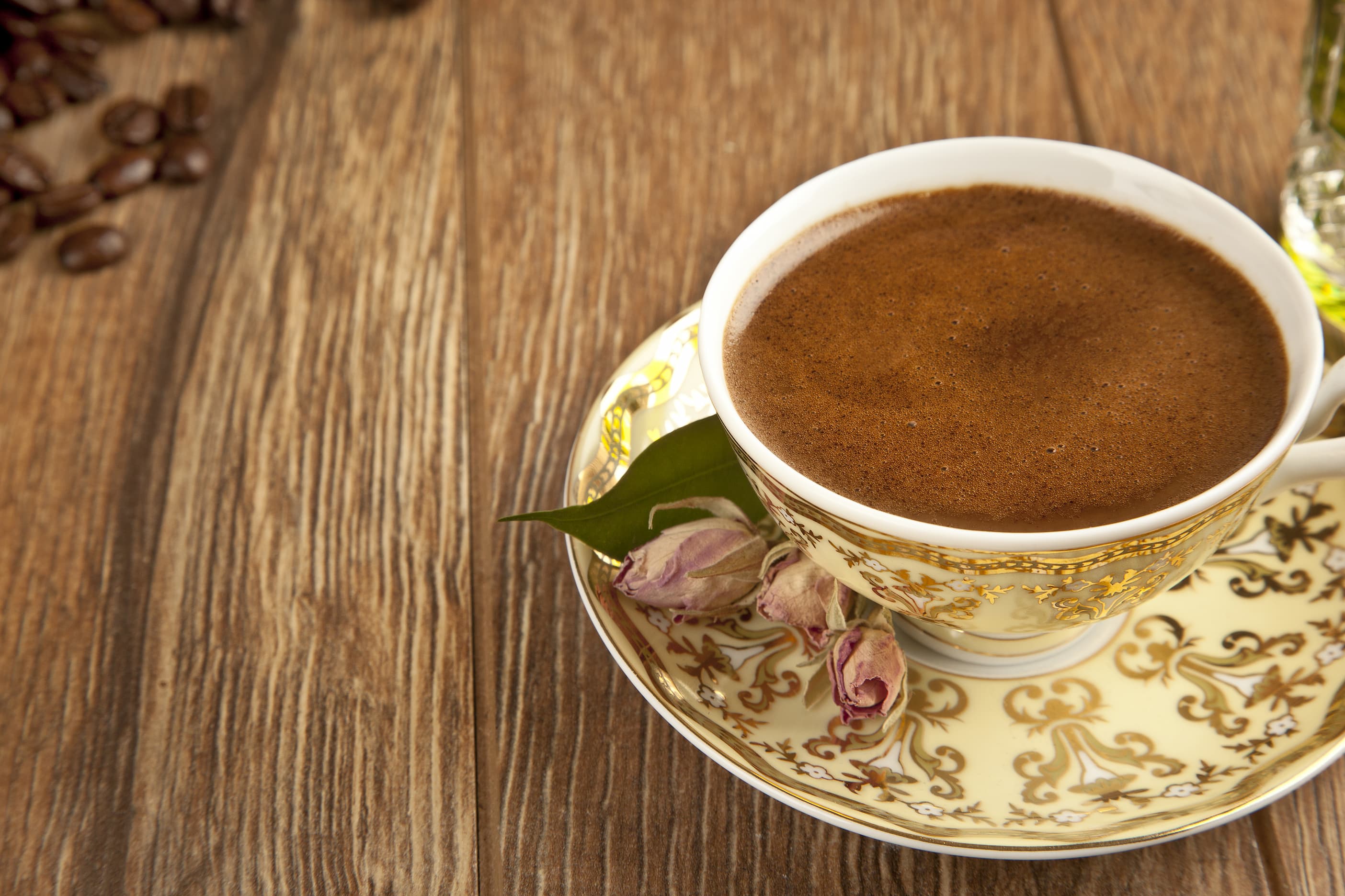 Türkischer Kaffee in traditioneller Porzellantasse auf Untertasse mit Rosenblättern.