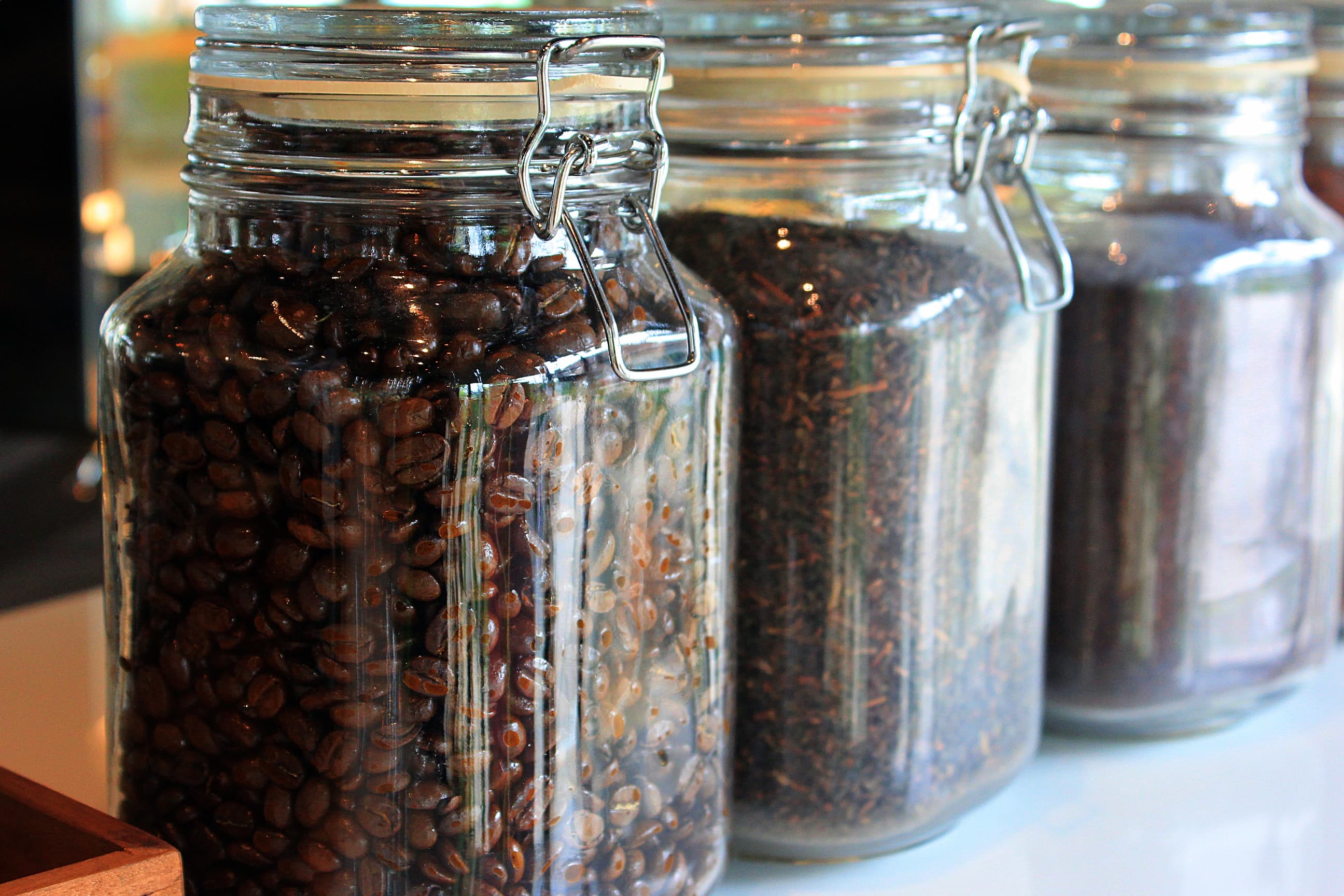 Große Gläser mit Kaffeebohnen und Tee, verschlossen mit Metallbügeln.
